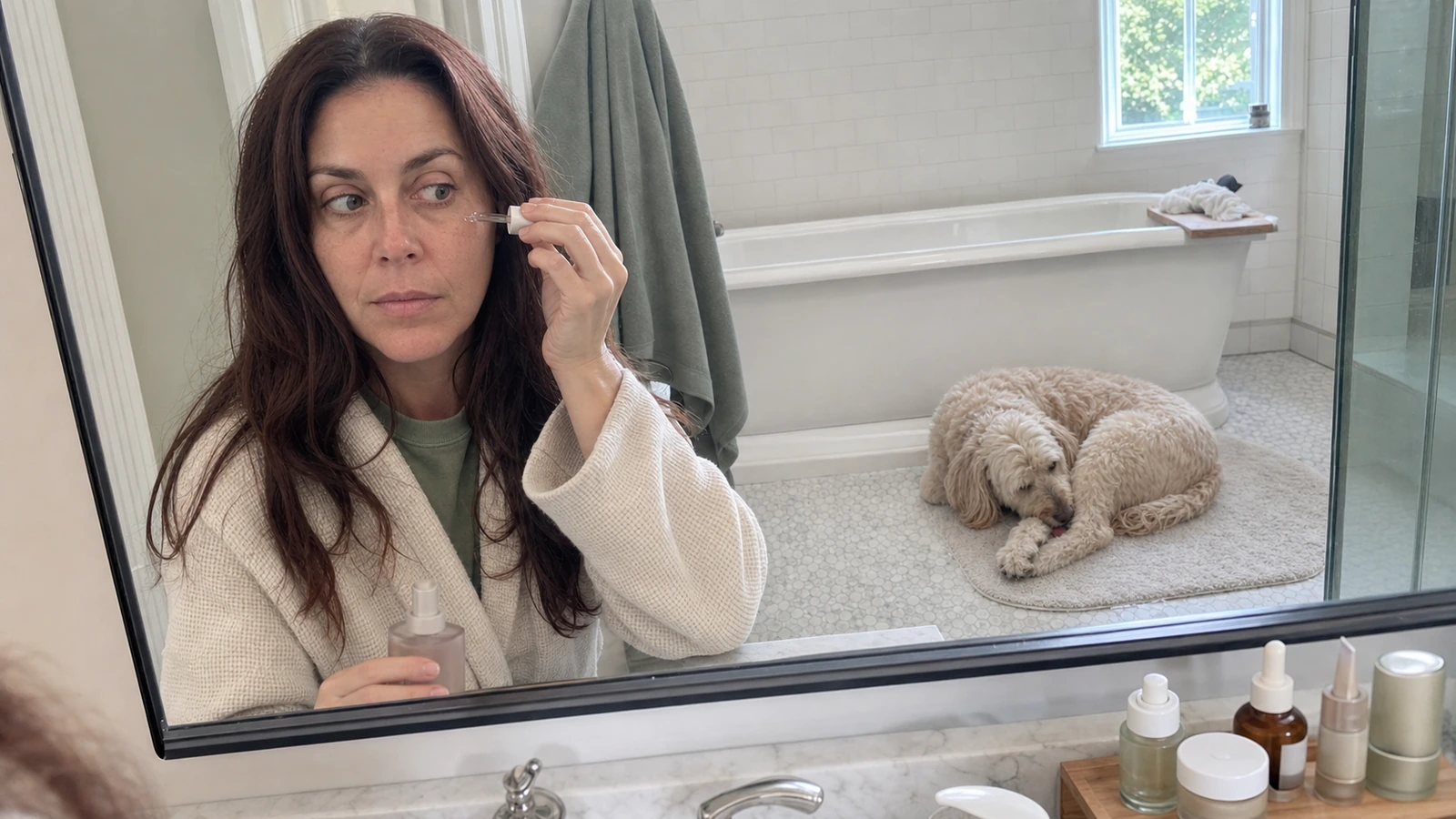 Erin doing her skincare routine while Maple licks her paw nearby